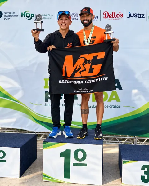 Atletas no lugar mais alto do pódio com a bandeira da MG