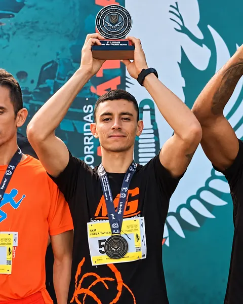 Atleta erguendo troféu em corrida da PM